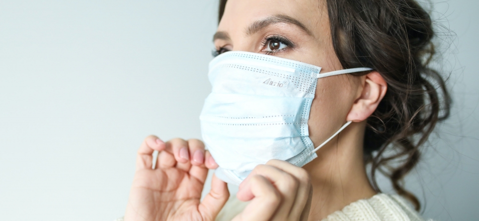 Woman adjusting a surgical mask around her chin