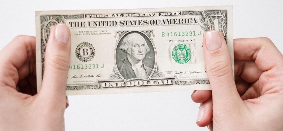 Hands holding one dollar bill