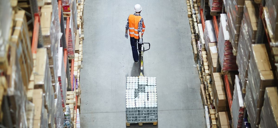 Worker pulling a skid of material on a warehouse floor