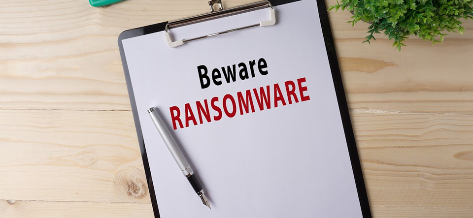 Clipboard with a piece of paper that reads BEWARE RANSOMWARE