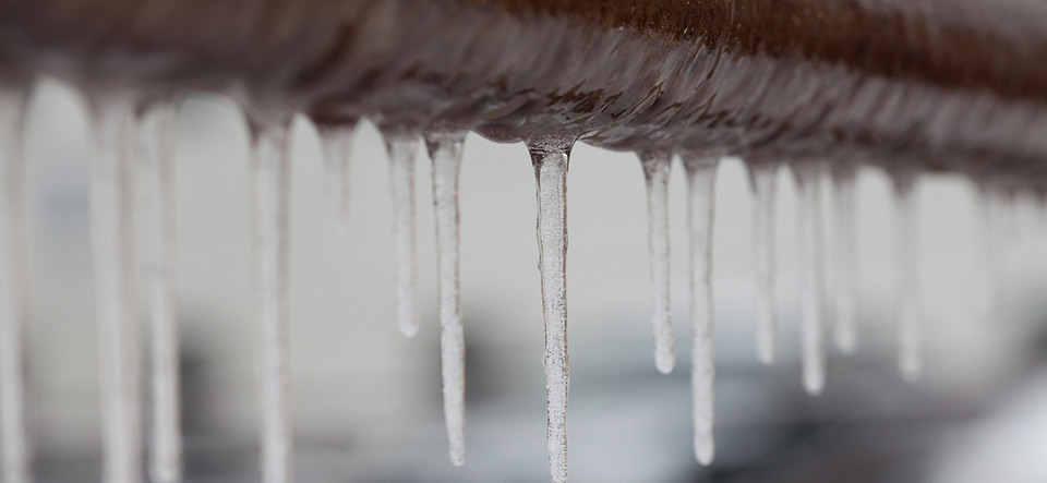 Icicles hanging from a brown pipe. Frozen water and metal surface, winter time concept. selective focus shallow depth of field photo.