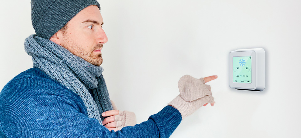Man turning on home heating system using digital thermostat