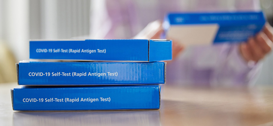 Close Up Of Woman At Home Reading Instructions On Supply Of Covid-19 Rapid Antigen Self-Testing Kits