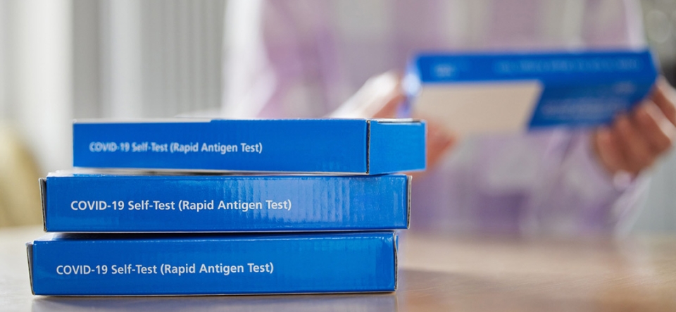 Close Up Of Woman At Home Reading Instructions On Supply Of Covid-19 Rapid Antigen Self-Testing Kits