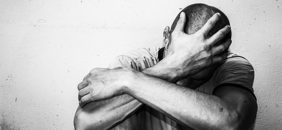 Homeless man drug and alcohol addict sitting alone and depressed on the street feeling anxious and lonely, social documentary concept black and white