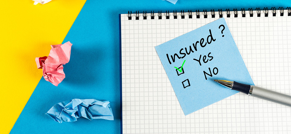 Survey with question Insured, Yes or no. Message at notepad at yellow and blue table, insurance agent.