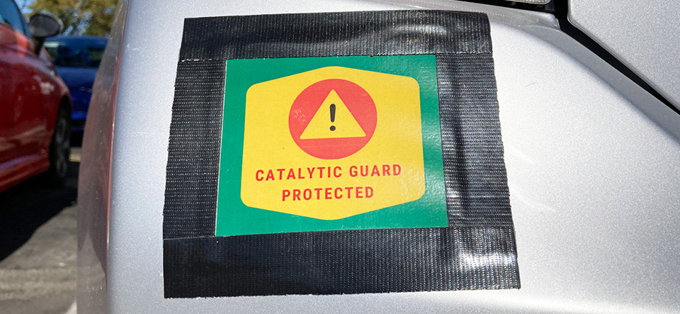Catalytic Guard Protected sign on vehicle bumper. Catalytic converter theft prevention.