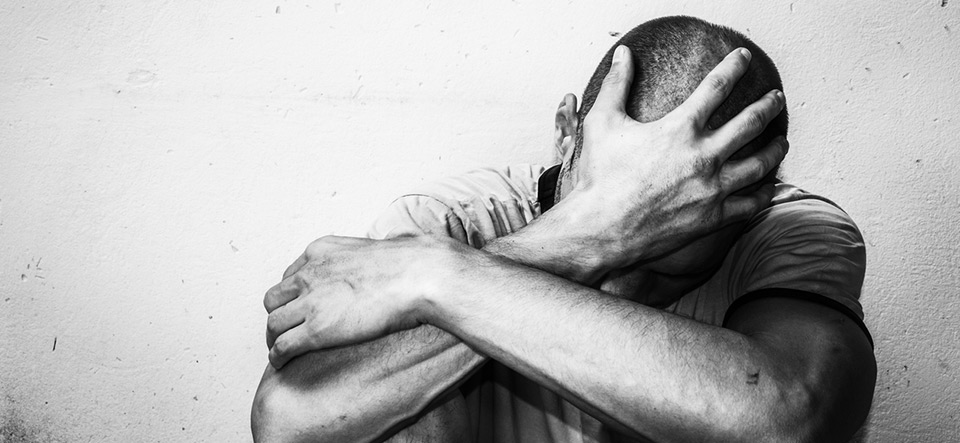 Homeless man drug and alcohol addict sitting alone and depressed on the street feeling anxious and lonely, social documentary concept black and white