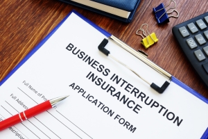 Business interruption insurance form and red pen for signing.