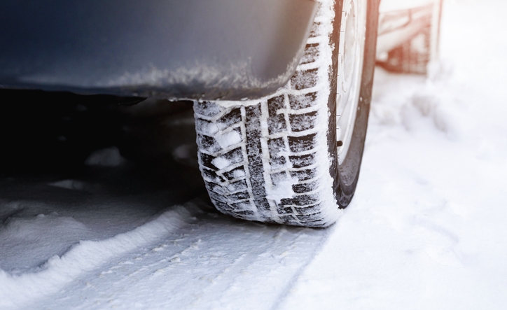 A car wheel with winter tires and a footprint on a snowy road. Snow drifts, ice, insurance event concept.