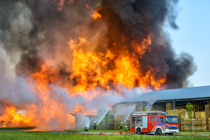 Fire fighters behind a fire engine trying to put out a fire in an industrial area in the town of Kampen in The Netherlands.