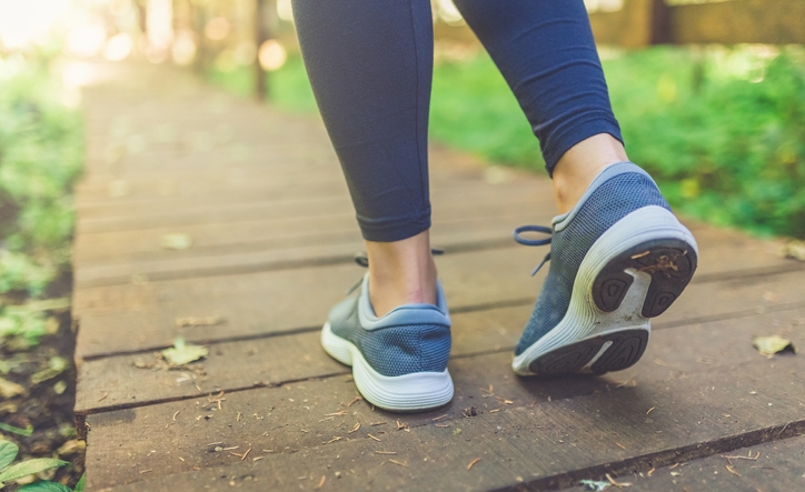 Close up of female legs with running shoes on wooden footpath in woods. Nature and sport healthy lifestyle concept.