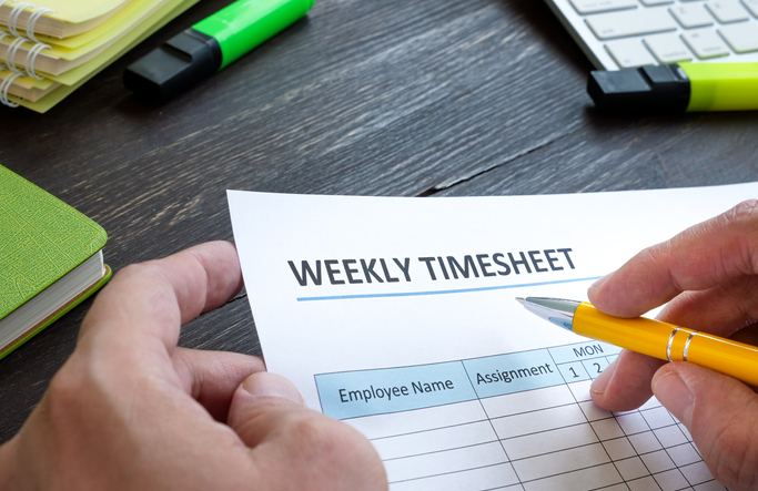 Man filing in weekly timesheet for employee in the office.