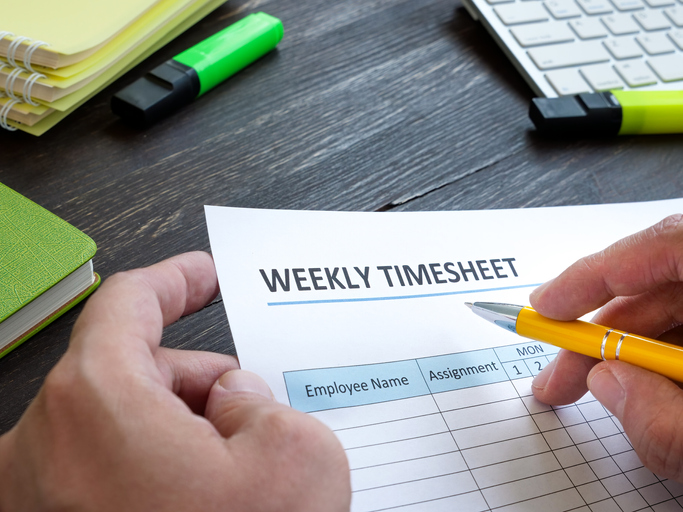 Man filing in weekly timesheet for employee in the office.