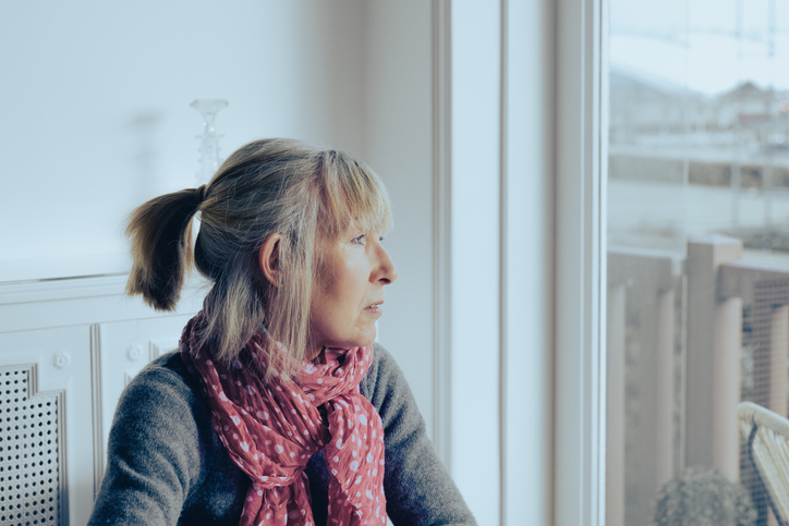 Lonely mature woman looking blankly out of the window.