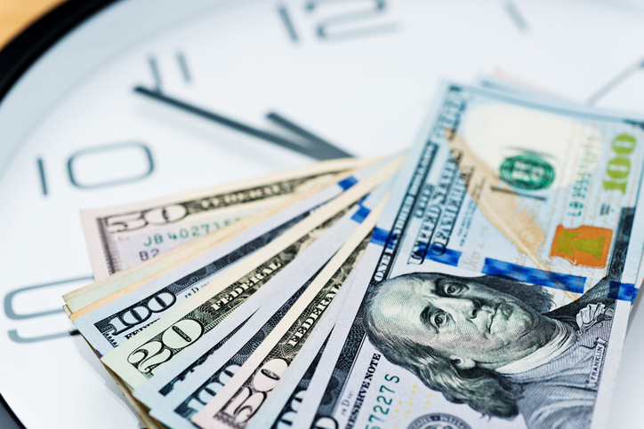 Dollar bills on top of a clock face