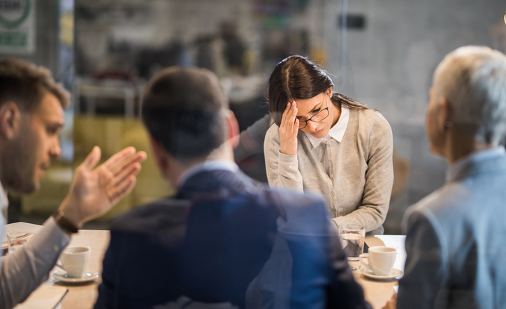 Young woman feeling disappointed after failing on a job interview in the office. The view is through glass.